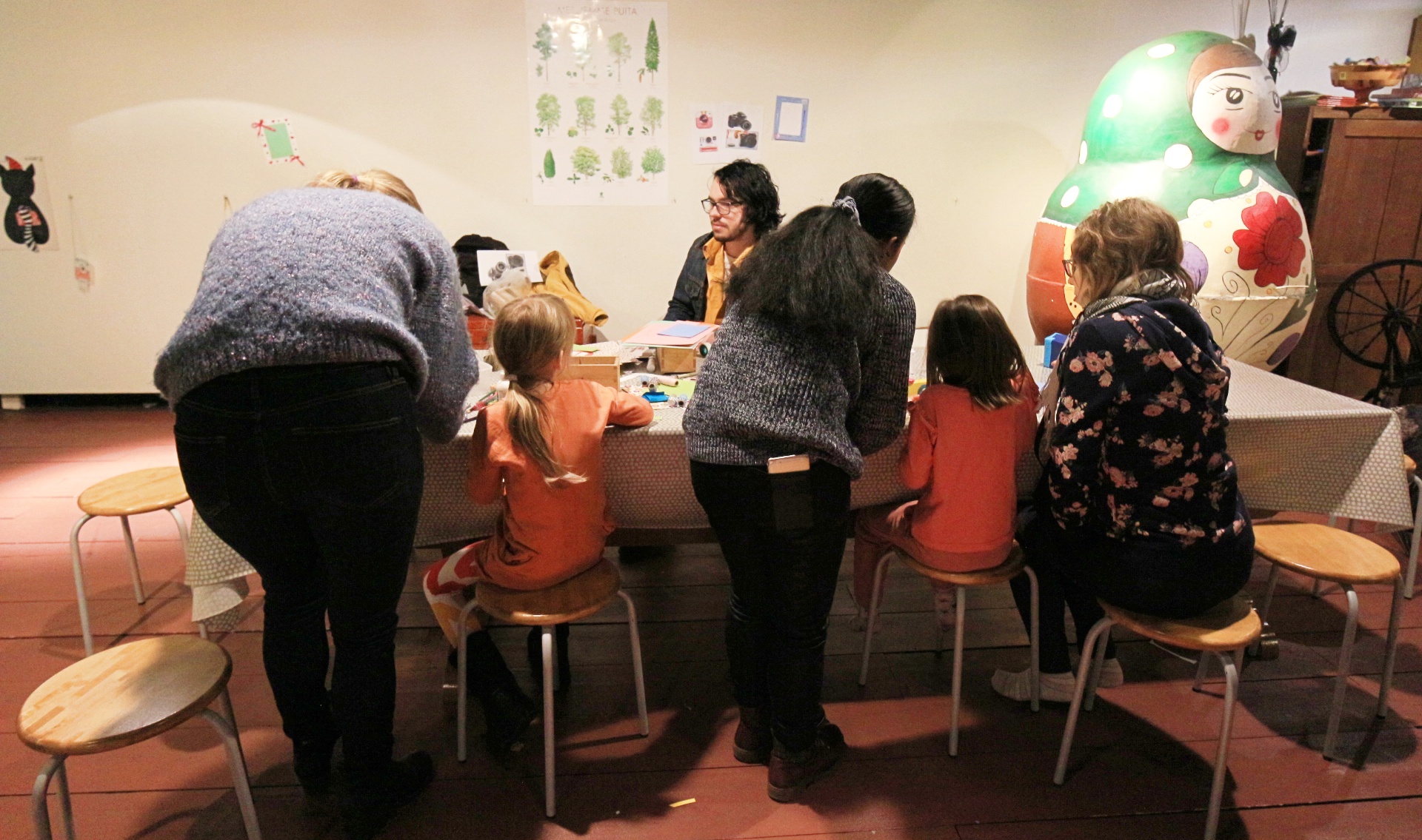children and adults sit around a table making crafts.